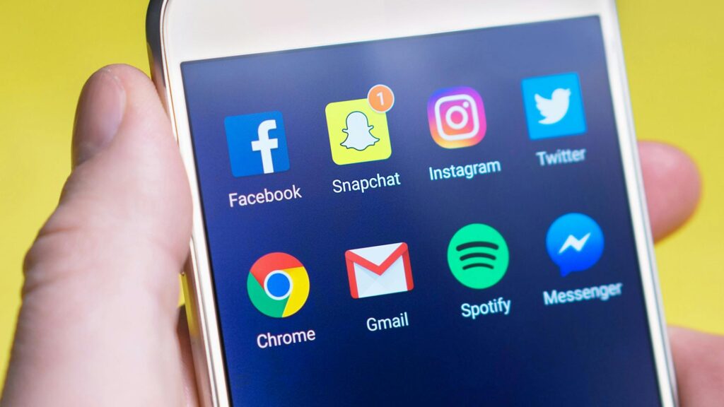 pexels-photo-533446-533446 A person's hand holding a smartphone displaying social media and communication apps.